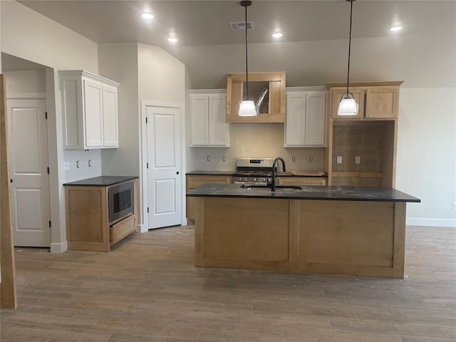 kitchen featuring hanging light fixtures, sink, a center island with sink, and white cabinets