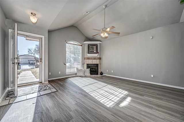 unfurnished living room with a fireplace, lofted ceiling, dark wood-type flooring, and a wealth of natural light