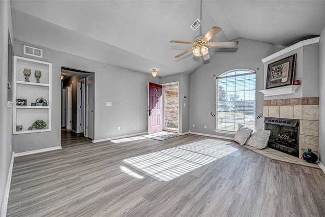 unfurnished living room with built in shelves, a fireplace, wood-type flooring, and vaulted ceiling