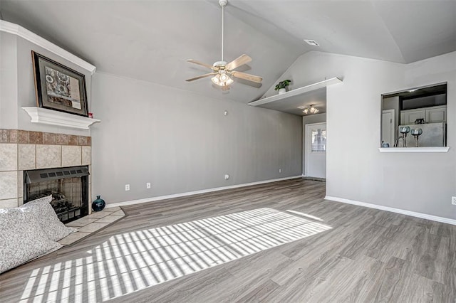 unfurnished living room featuring ceiling fan, light hardwood / wood-style floors, lofted ceiling, and a tiled fireplace