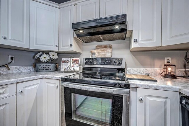 kitchen with electric range, light stone countertops, and white cabinetry