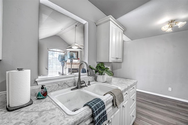 kitchen featuring white cabinetry, sink, ceiling fan, dark wood-type flooring, and vaulted ceiling