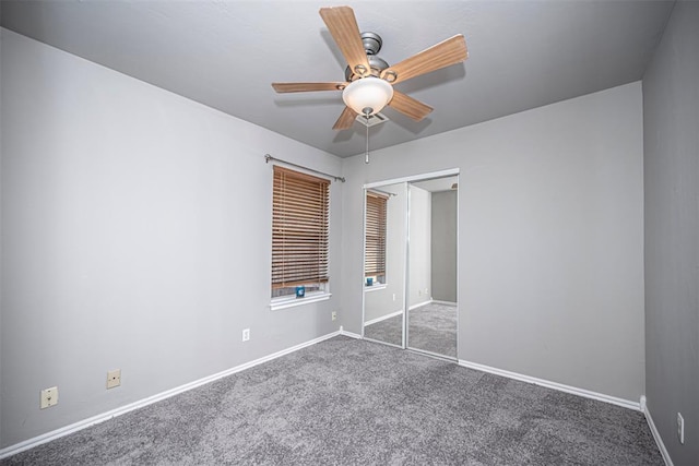 unfurnished bedroom with dark colored carpet, a closet, and ceiling fan