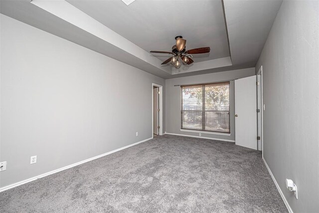 carpeted empty room with a raised ceiling and ceiling fan