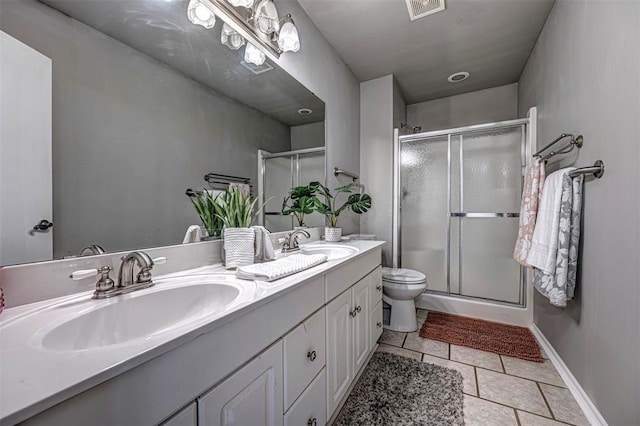 bathroom featuring tile patterned floors, vanity, a shower with shower door, and toilet