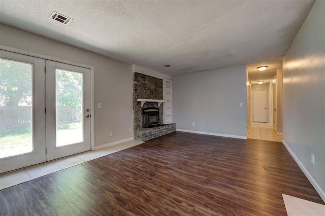 unfurnished living room featuring a fireplace, wood-type flooring, a textured ceiling, and french doors