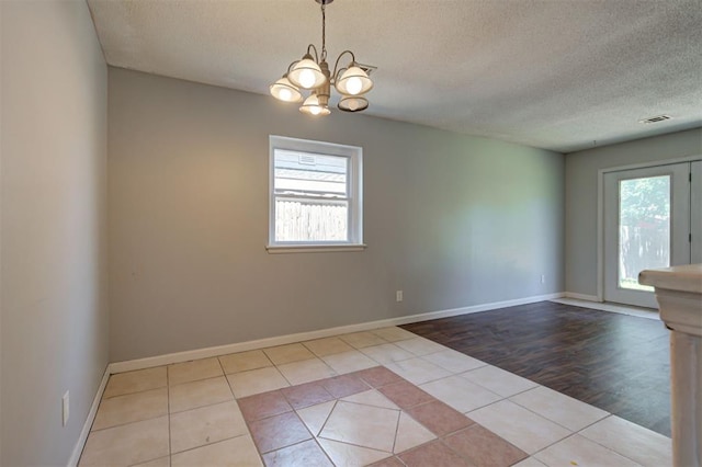 spare room featuring light hardwood / wood-style flooring, a textured ceiling, and an inviting chandelier