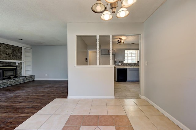 unfurnished living room with built in features, a chandelier, a textured ceiling, a fireplace, and light wood-type flooring