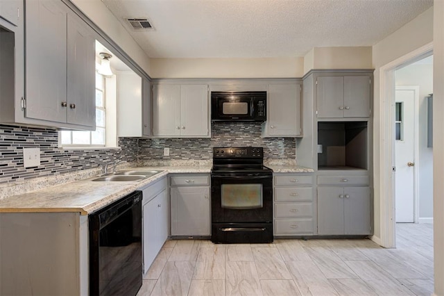 kitchen featuring black appliances, backsplash, gray cabinetry, and sink