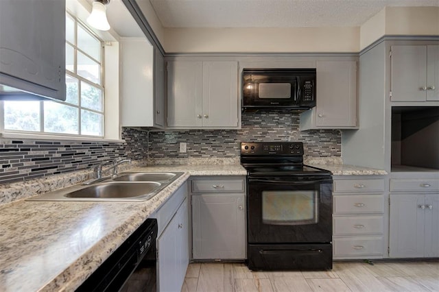 kitchen featuring decorative backsplash, sink, gray cabinets, and black appliances