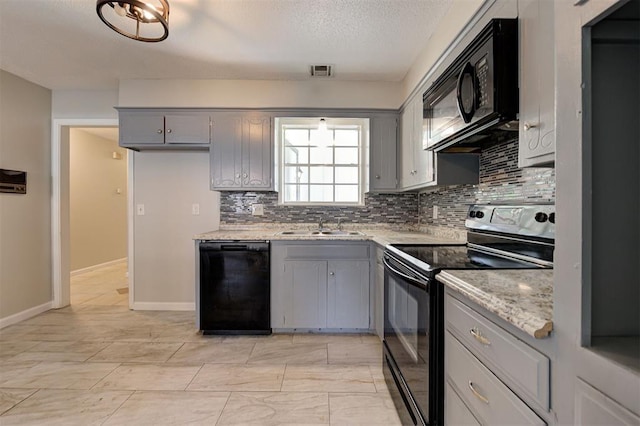 kitchen with gray cabinetry, sink, light stone counters, backsplash, and black appliances