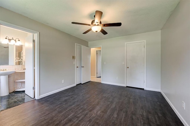 unfurnished bedroom with a textured ceiling, dark hardwood / wood-style flooring, ensuite bathroom, and ceiling fan