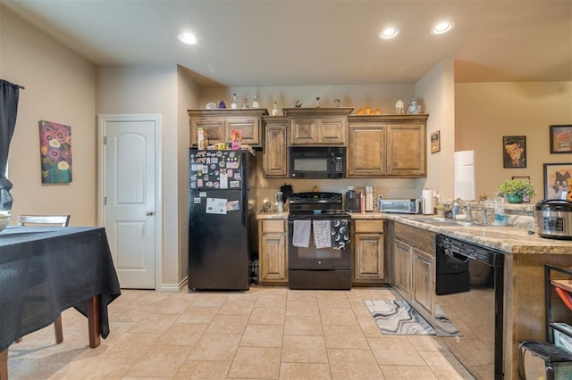 kitchen featuring black appliances, light stone countertops, and sink