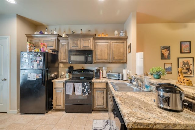 kitchen with sink, light stone counters, and black appliances