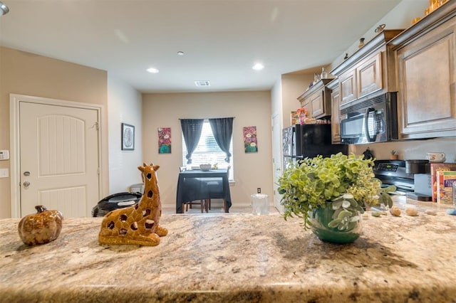 kitchen with black appliances, light brown cabinets, and light stone counters