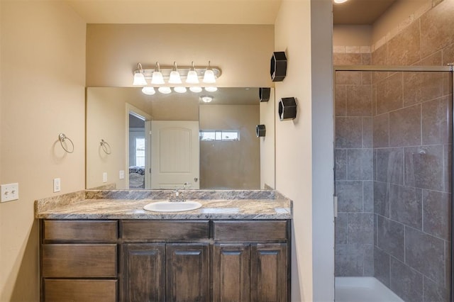 bathroom with a tile shower and vanity