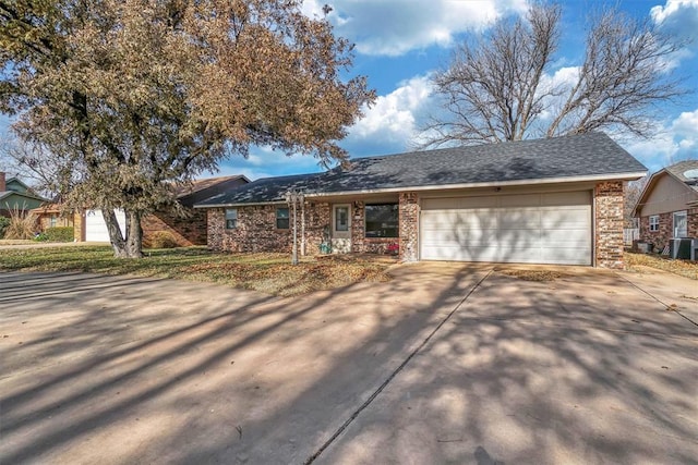 single story home with central AC unit and a garage