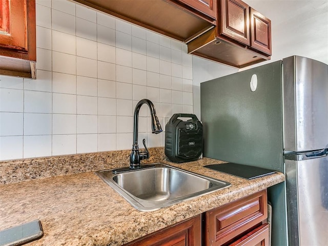 kitchen featuring backsplash, stainless steel fridge, and sink