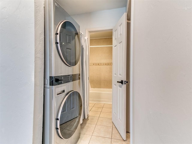 laundry area with light tile patterned floors and stacked washer and clothes dryer