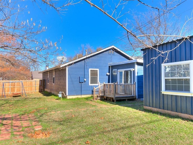 back of house featuring a lawn and a wooden deck