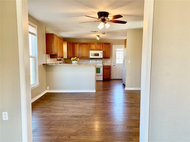 kitchen featuring kitchen peninsula, ceiling fan, backsplash, white appliances, and dark hardwood / wood-style flooring