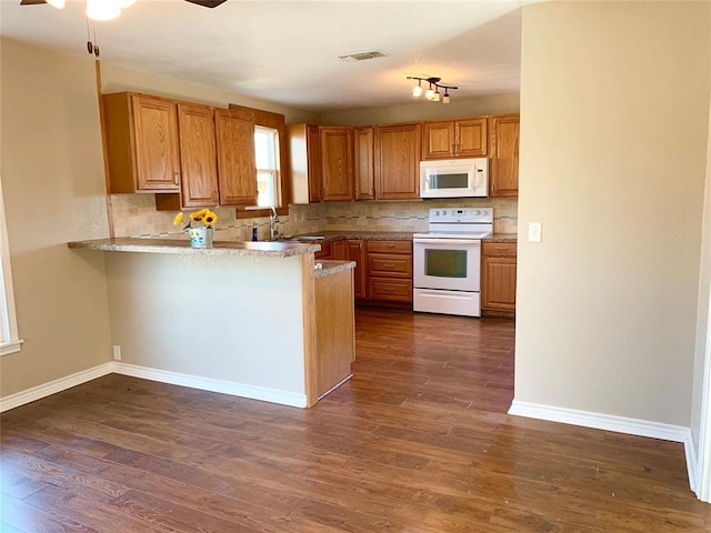 kitchen featuring kitchen peninsula, backsplash, white appliances, dark wood-type flooring, and sink