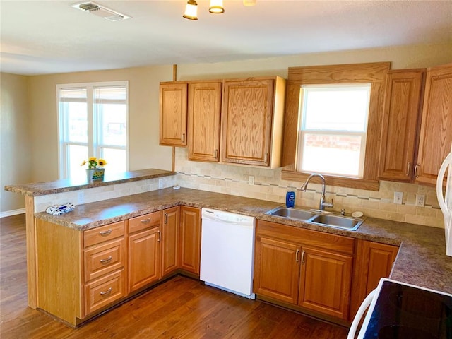 kitchen featuring tasteful backsplash, dark hardwood / wood-style floors, kitchen peninsula, sink, and white dishwasher