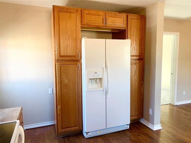 kitchen featuring dark wood-type flooring, white refrigerator with ice dispenser, and stove