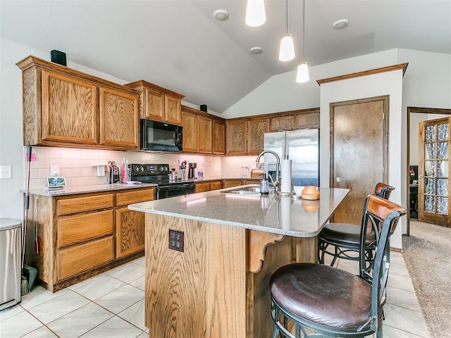 kitchen featuring vaulted ceiling, a kitchen island with sink, sink, black appliances, and light tile patterned floors