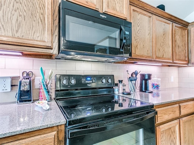 kitchen featuring black appliances, light stone counters, and tasteful backsplash