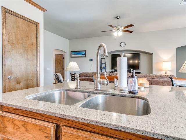 kitchen with light stone countertops, ceiling fan, and sink