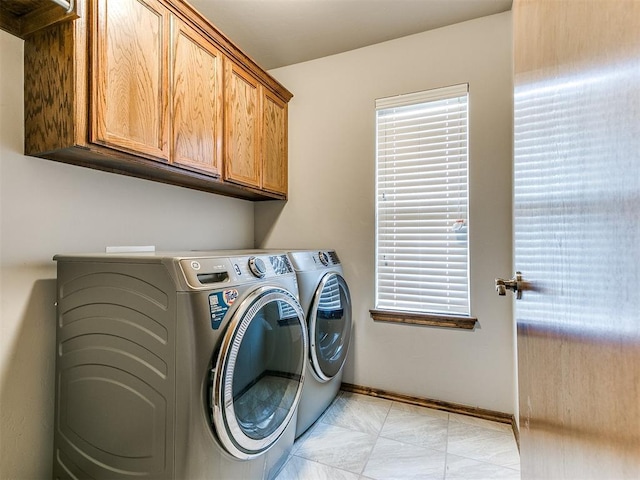 laundry area with separate washer and dryer and cabinets