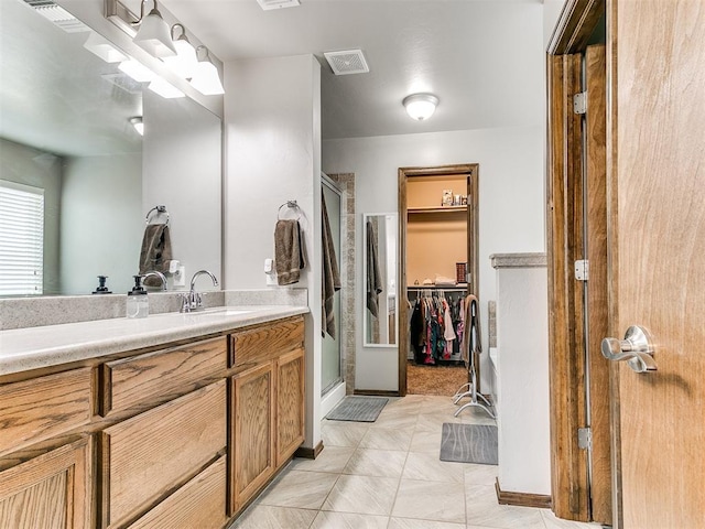 bathroom featuring a shower with door and vanity