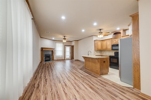 kitchen with crown molding, light hardwood / wood-style floors, a breakfast bar, a kitchen island, and black appliances