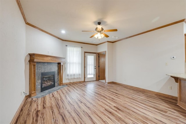 unfurnished living room featuring light hardwood / wood-style floors, ceiling fan, ornamental molding, and a tiled fireplace