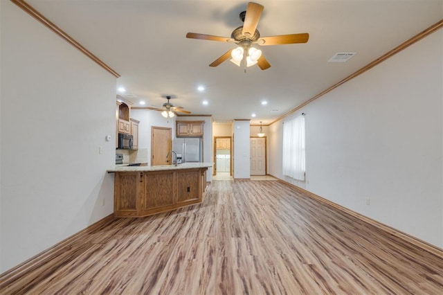 unfurnished living room with ceiling fan, sink, light wood-type flooring, and crown molding