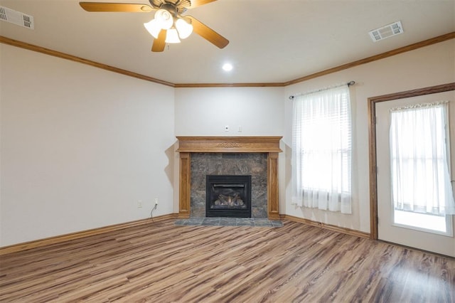 unfurnished living room featuring a tiled fireplace, ceiling fan, a healthy amount of sunlight, and hardwood / wood-style flooring