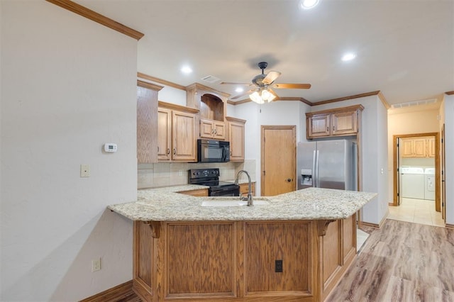 kitchen featuring kitchen peninsula, washing machine and dryer, ceiling fan, and black appliances