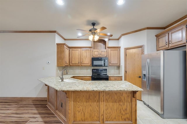 kitchen with kitchen peninsula, light stone counters, ceiling fan, sink, and black appliances