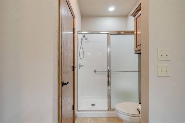 bathroom with tile patterned flooring, toilet, and an enclosed shower