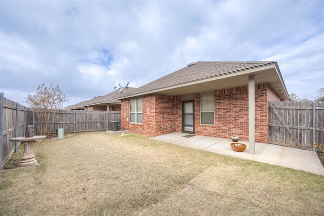 rear view of house with a lawn, central AC, and a patio