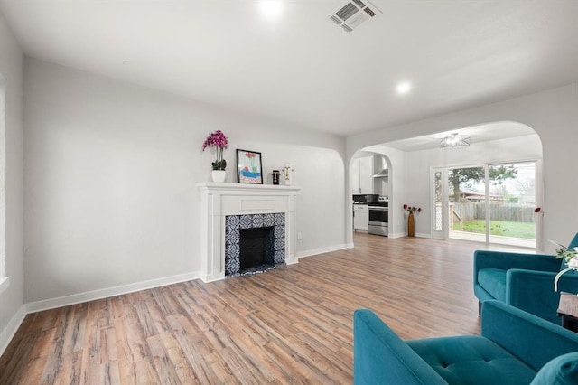 unfurnished living room with a tile fireplace and light hardwood / wood-style flooring