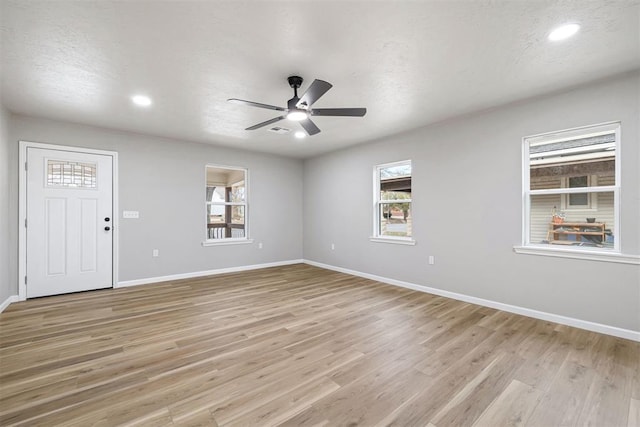 empty room with ceiling fan, light wood-type flooring, and a textured ceiling