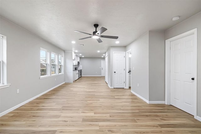 unfurnished living room featuring ceiling fan, light hardwood / wood-style floors, and a textured ceiling