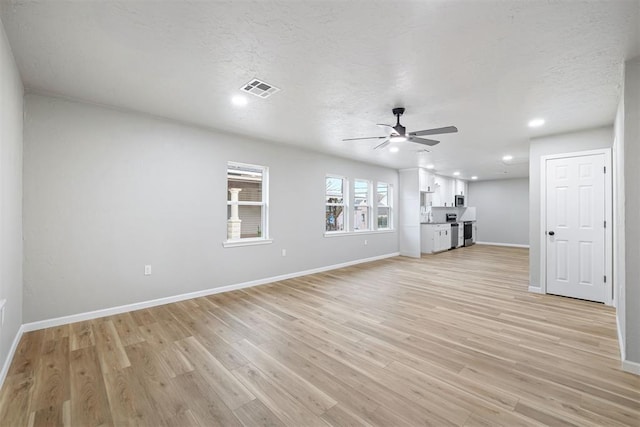 unfurnished living room with ceiling fan, a textured ceiling, and light hardwood / wood-style flooring