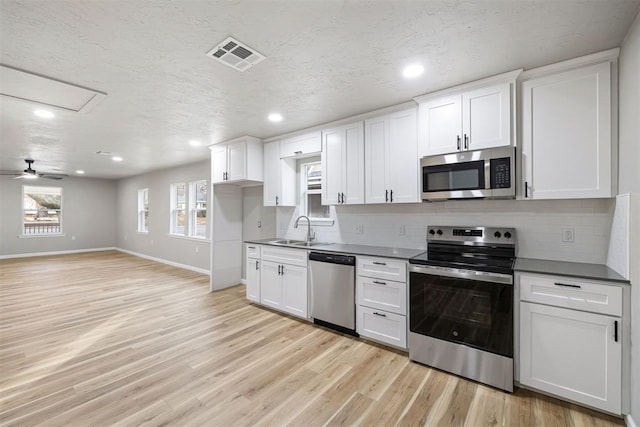 kitchen with white cabinetry, sink, ceiling fan, stainless steel appliances, and light hardwood / wood-style flooring