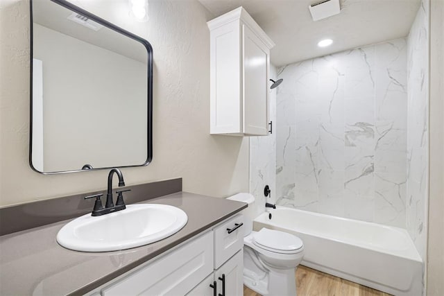 full bathroom featuring tiled shower / bath, hardwood / wood-style flooring, vanity, and toilet