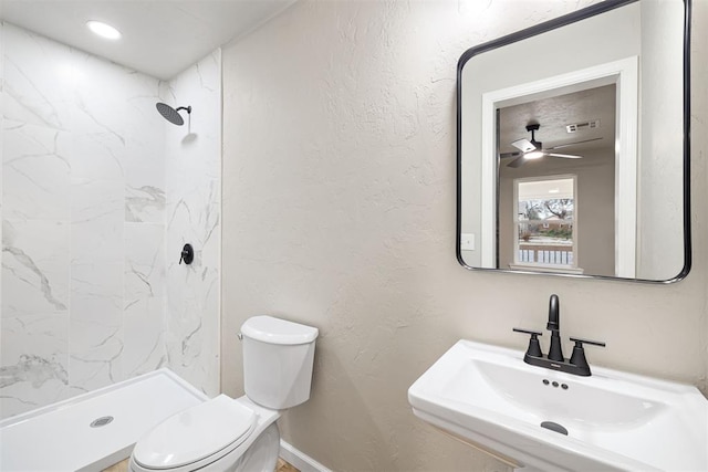 bathroom featuring ceiling fan, toilet, sink, and walk in shower