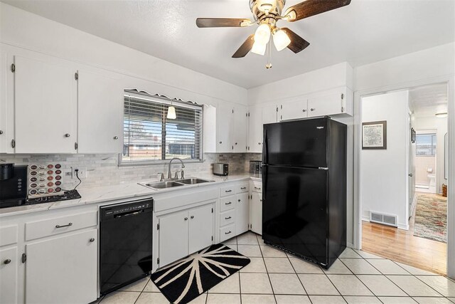 kitchen with tasteful backsplash, sink, black appliances, light tile patterned floors, and white cabinets