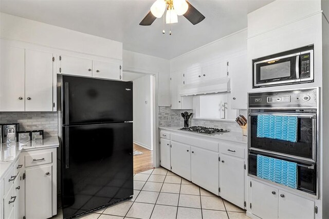 kitchen featuring decorative backsplash, white cabinetry, black appliances, and custom range hood